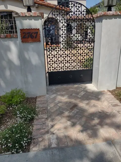 Arched courtyard gate with a lattice pattern and solid lower panel