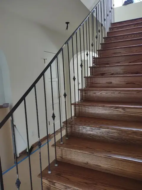 Straight wooden staircase with a slim-bar iron railing
