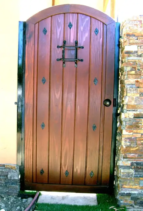 Arched wood pedestrian gate with an iron grille window