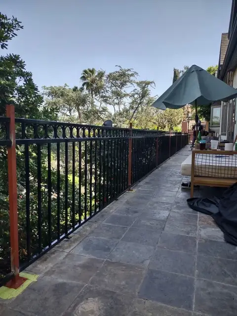Terrace railing with vertical bars along a slate patio