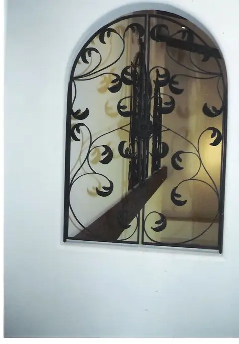 Arched window grille with crescent scrollwork