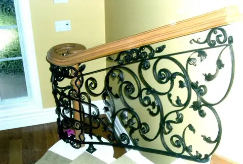 Scrollwork stair railing section with a wood handrail inside a home