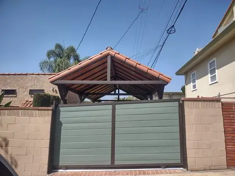 Modern solid-panel driveway gates in sage green under a tile carport