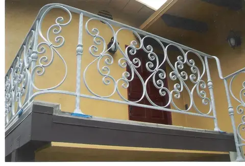 White scrollwork balcony railing on an exterior balcony