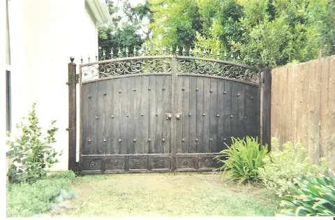 Wood double driveway gates with an iron frame and scrollwork crest