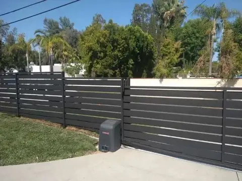 Horizontal slat driveway gate and fence with the gate operator in view