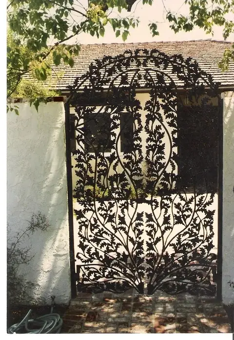 Ornate arched pedestrian gate covered in hand-forged leaf and vine scrollwork