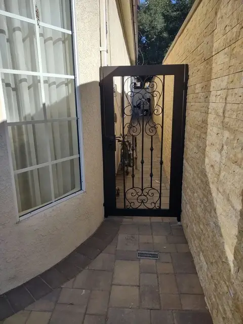 Side gate with a scroll medallion along a brick walkway