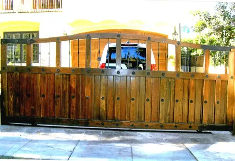 Wood sliding driveway gate with iron studs and frame