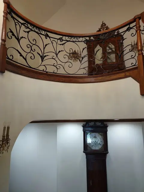 Curved second-floor balcony railing with scrollwork overlooking a foyer