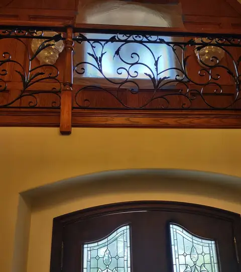 Mezzanine railing with vine scrollwork above arched entry doors
