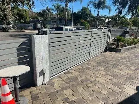 Gray horizontal slat sliding gate at a paver driveway
