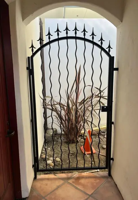 Arched pedestrian gate with wavy bars and spear finials