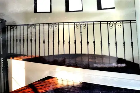 Curved landing railing with knuckle balusters and a scroll top rail