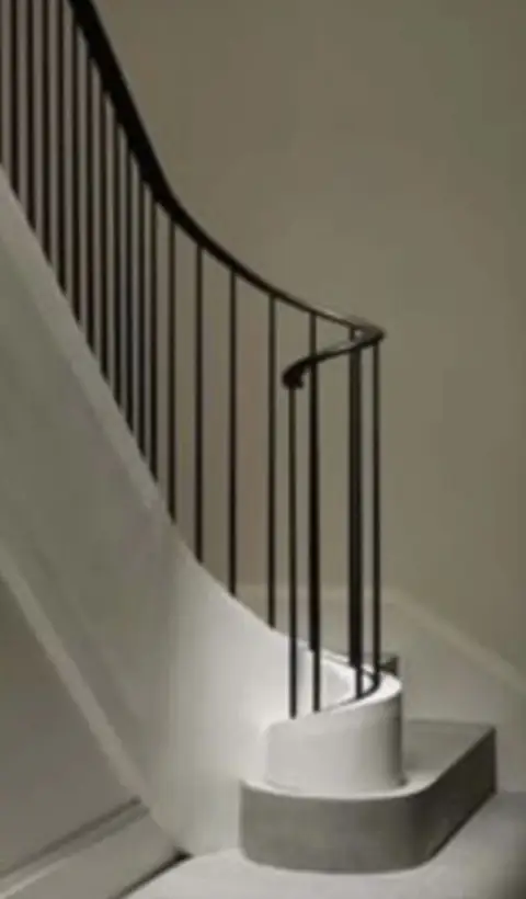 Minimalist curved stair railing on a white modern staircase