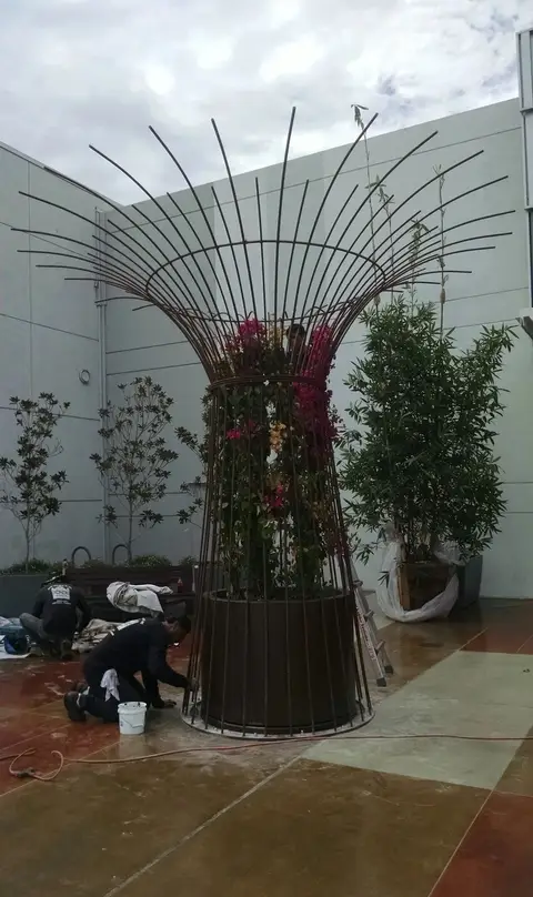 Custom iron planter trellis being installed in a courtyard