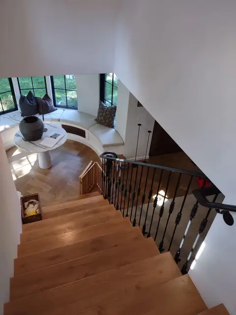 Wood staircase with a black railing viewed from the landing above