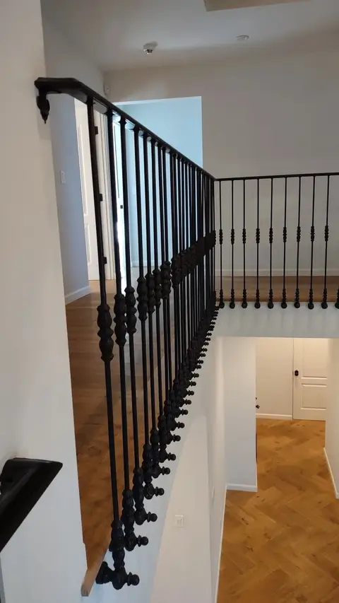 Landing railing with knuckle balusters over a herringbone wood floor