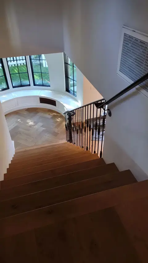 Wood staircase with a black iron railing descending to a window seat