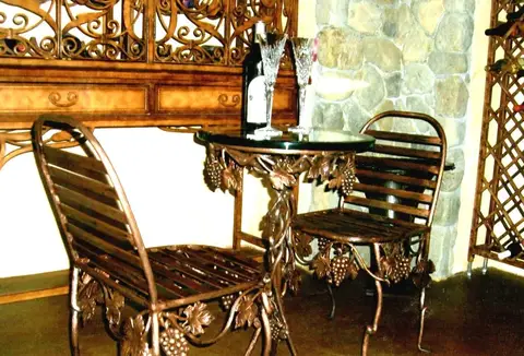 Grapevine iron bistro set with a glass-top table in a wine cellar