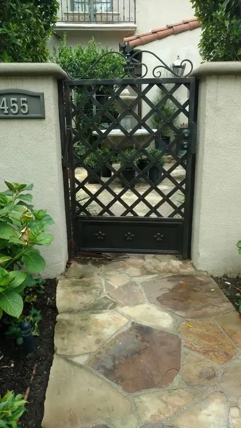 Lattice pedestrian gate with a solid base panel on a stone path