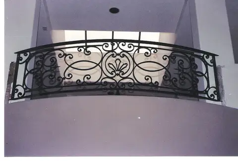 Curved interior balcony railing with a central fleur-de-lis medallion
