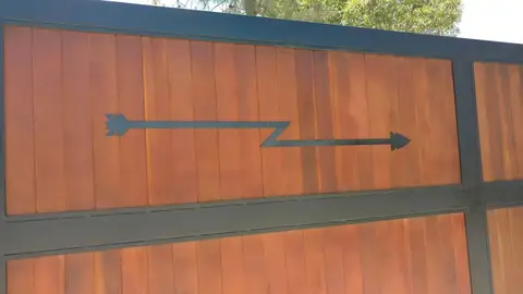 Close-up of a wood sliding gate with a forged arrow handle