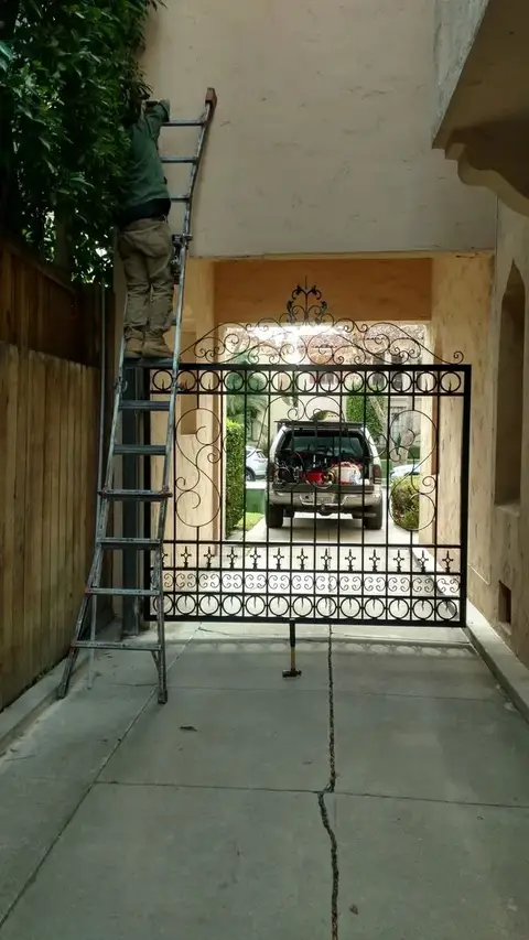 Automatic driveway gate being serviced in a covered driveway