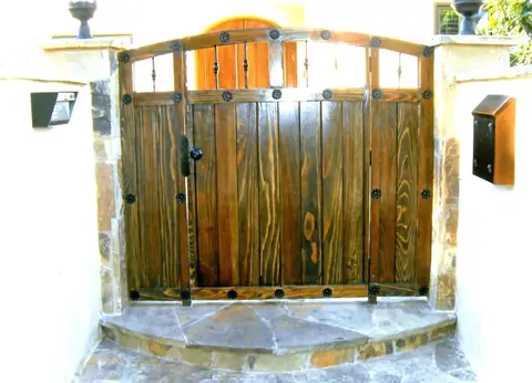 Wood courtyard gates with iron strap hinges at a stone entry