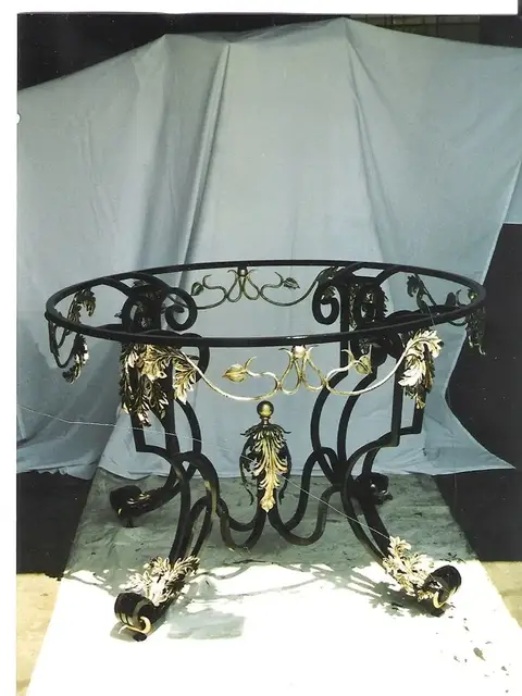 Ornate round iron table base with gold-leaf grape accents