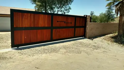 Modern sliding driveway gate with wood panels in a steel frame