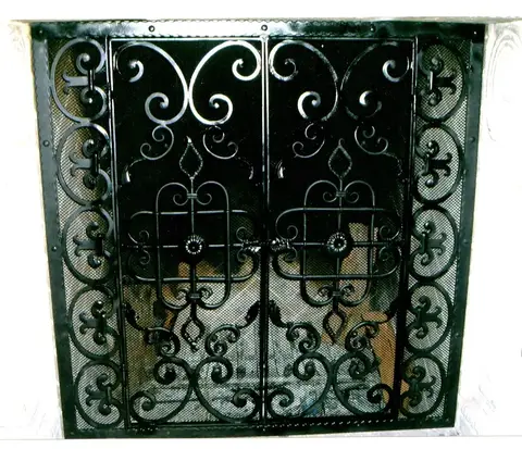 Ornate double-door fireplace screen with scrollwork and fleur-de-lis details