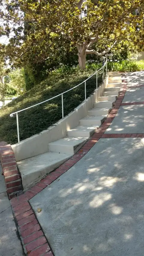 Hillside walkway steps with a simple iron handrail