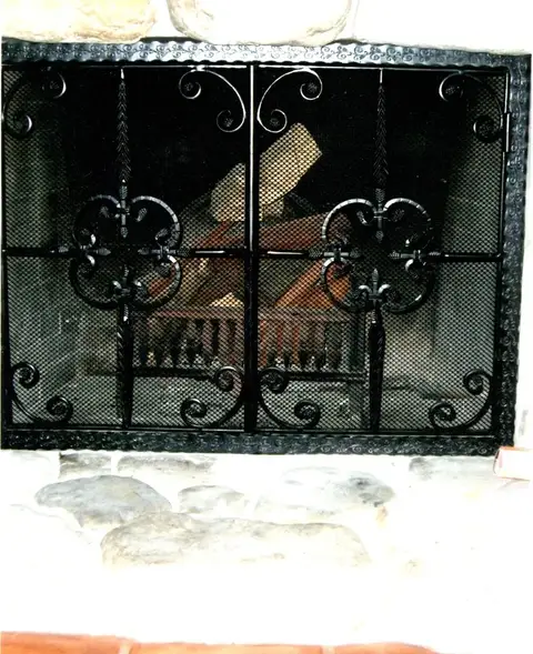 Fireplace screen with quatrefoil medallions over mesh in a stone surround