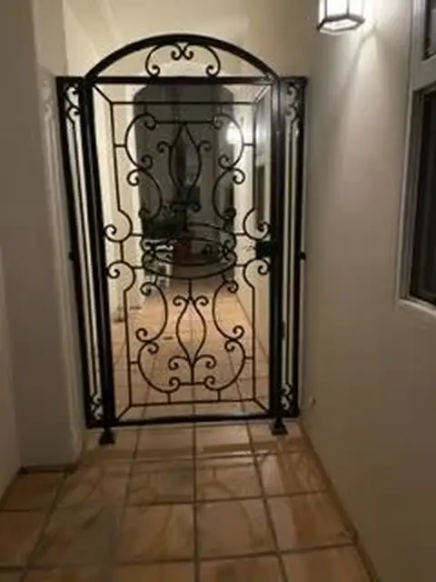 Arched interior wine cellar gate with scrollwork panels